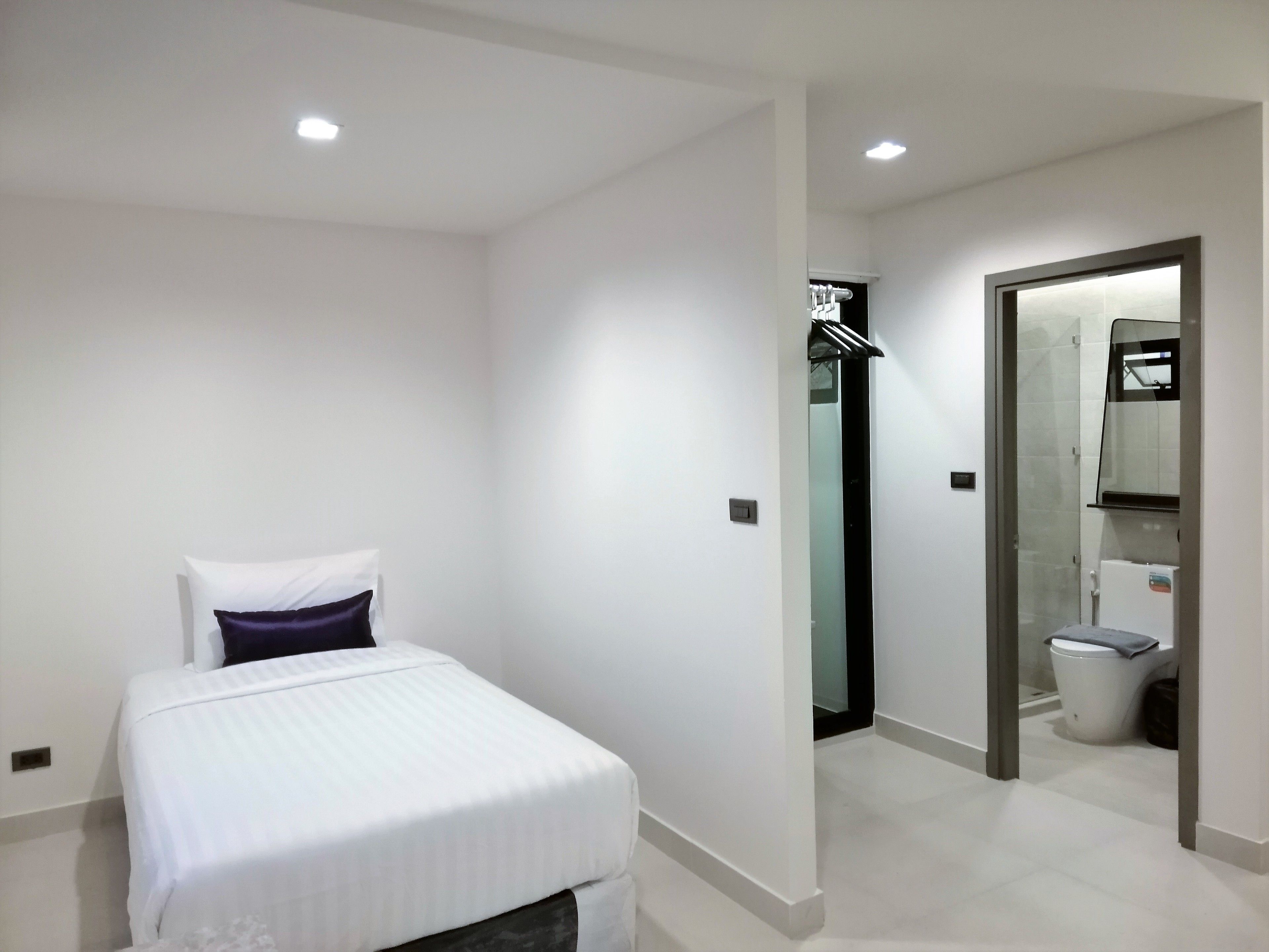 A modern hotel room with a bed, a bathroom, and a shower area.