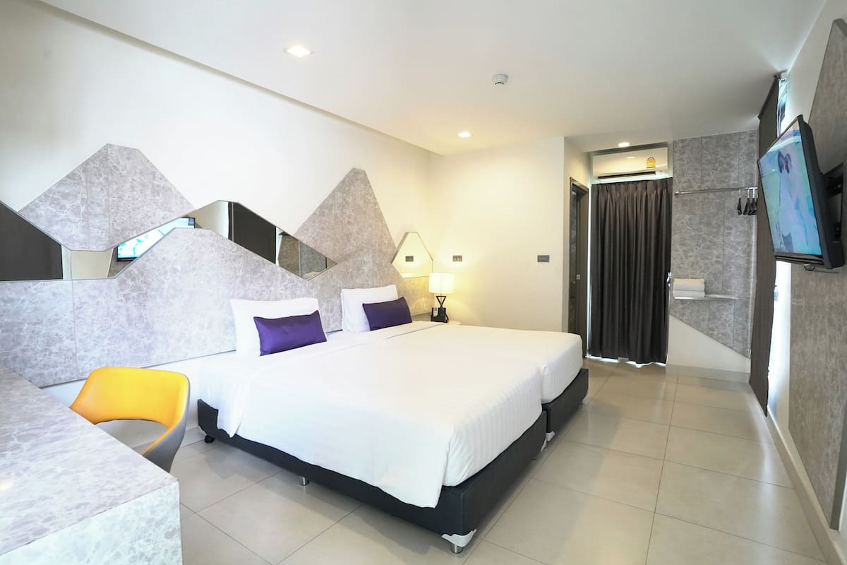 A modern hotel room with a large bed, a desk, and a TV.