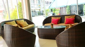 A modern lounge area with wicker furniture and a glass coffee table. - JJ Villa (Khon Kaen)