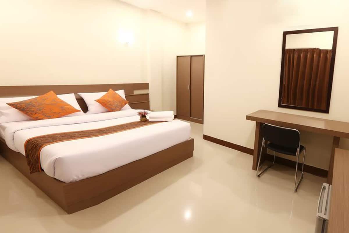 A hotel room with a bed, a desk, a chair, a television, and a wardrobe.