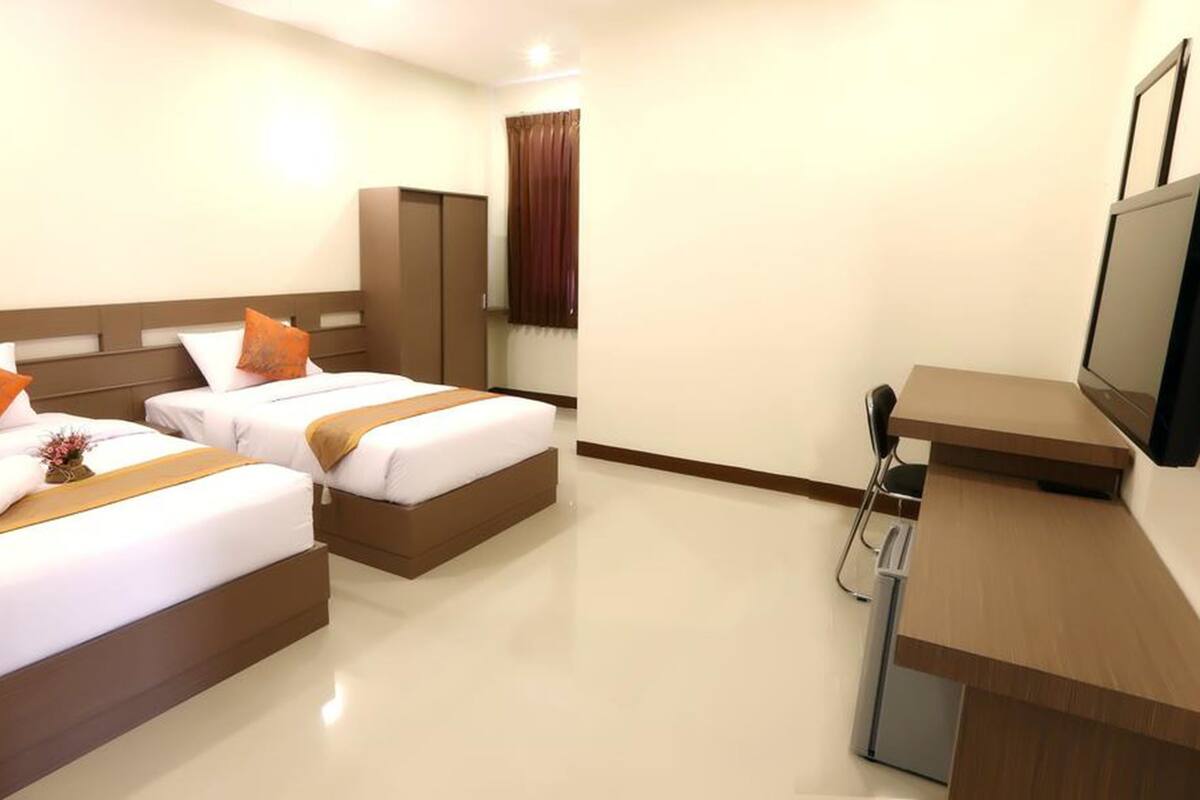 A hotel room with two beds, a desk, a television, and a mirror.