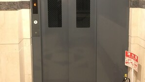 Une porte de monte-charge fermée, avec un extincteur placé sur le côté droit.