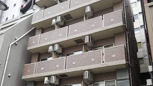Un immeuble à plusieurs étages doté de balcons, de climatiseurs et d’une enseigne indiquant la présence d’un restaurant.