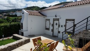 A white building with a tiled roof, a stone wall, and a staircase leading to a door marked "AL". - Casa Vista da Marquesa, Açores - Ideal house for a couple to enjoy nature! (Nordeste)