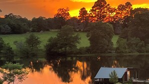 A rural landscape with a sunset, a body of water, and a solar panel. - Melody's Bed and "Catch Your Breakfast!" (Crockett)