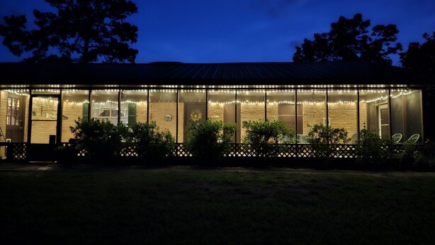 A modern building with large glass windows, a brick exterior, and string lights. - Melody's Bed and "Catch Your Breakfast!" (Crockett)