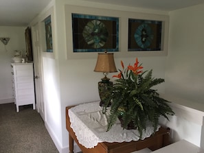 Stunning hallway with a bench, potted plant, and vibrant stained glass artworks.