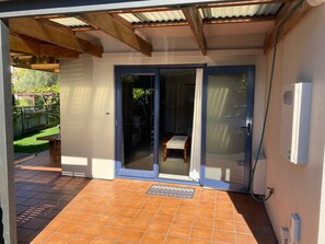 Un patio cubierto con puerta corrediza de vidrio que da a una habitación interior.