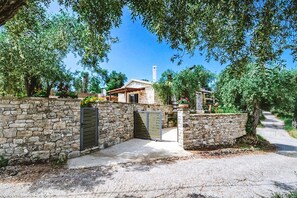 A stone-walled property with a gated entrance, a stone house, and a clear sky. - Aristea Villa - Two Bedroom Villa, Sleeps 6 (Kourteika)