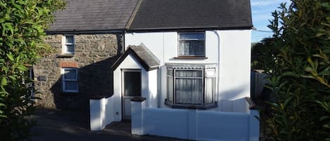 Una casa de dos pisos con fachada de piedra y sección superior blanca.