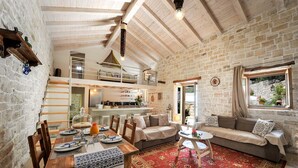 Un interior rústico con comedor, sofá y cocina al fondo.
