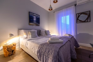 Relax in this serene bedroom with a large bed, nightstand, and a beautiful painting on the wall.