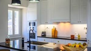 Una cuina moderna amb armaris blancs, una illa central i il·luminació penjant.