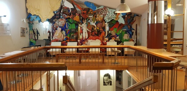A multi-level interior with a wooden staircase, a colorful abstract mural on the upper wall, and a framed picture on the lower wall. - Hotel Eco Logis Bellevue Pyrénées (Semeac)
