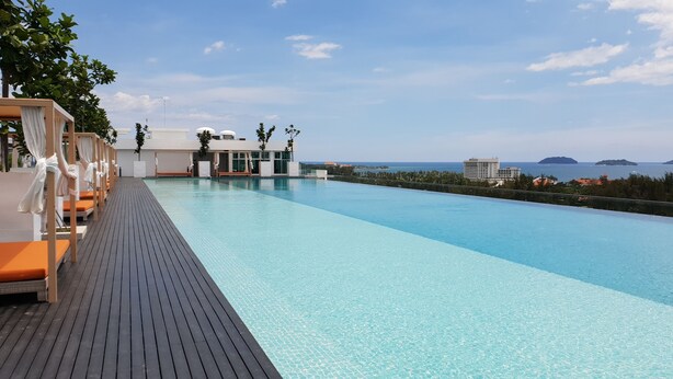 Un espace aménagé au bord de la piscine, avec des chaises longues et une vue sur la mer.