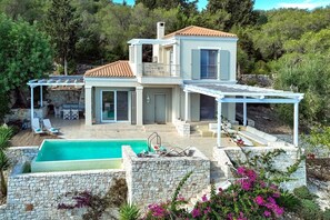Enjoy a serene atmosphere surrounded by lush greenery and a patio area with a swimming pool.