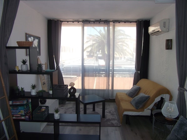A modern living room with a sofa, coffee table, and shelves with various items. - Harbor view, swimming pool, air conditioning, wifi (Gruissan)