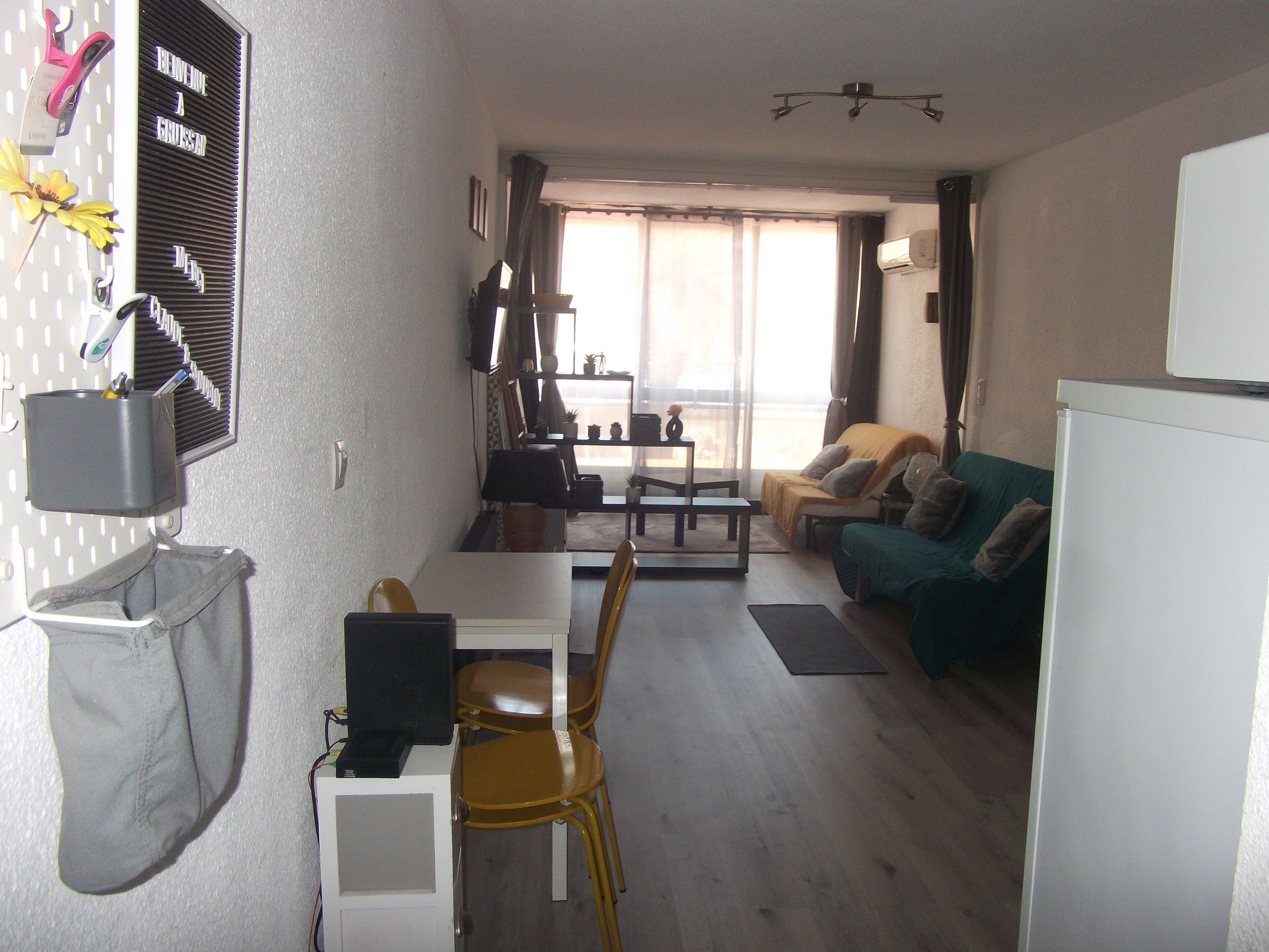 A compact living space with a dining area, a sofa, and a refrigerator.