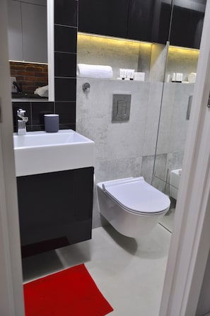 A modern bathroom with a white sink, black cabinets, and a white toilet. - Panda Apartments Bagno- Centrum (Warsaw)
