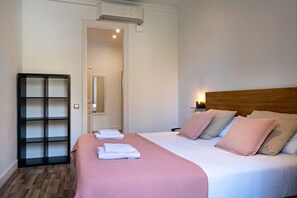 A hotel room with a bed, a bedside table, a nightstand, a mirror, and a wardrobe.