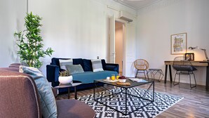 A modern living room with a sofa, coffee table, and chairs. There is a plant, a picture frame, and a desk with a chair. - Barcelona Balconies 1 - Habitat Apartments (Barcelona)