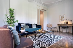 A modern living room with a sofa, coffee table, and a dining area with chairs.