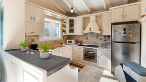 Una cocina moderna con alacenas blancas, estufa a gas, microondas y refrigerador de acero inoxidable.