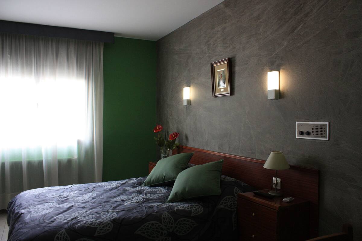 Ein Hotelzimmer mit Bett, Nachttisch, Lampe und einem Bilderrahmen an der Wand.