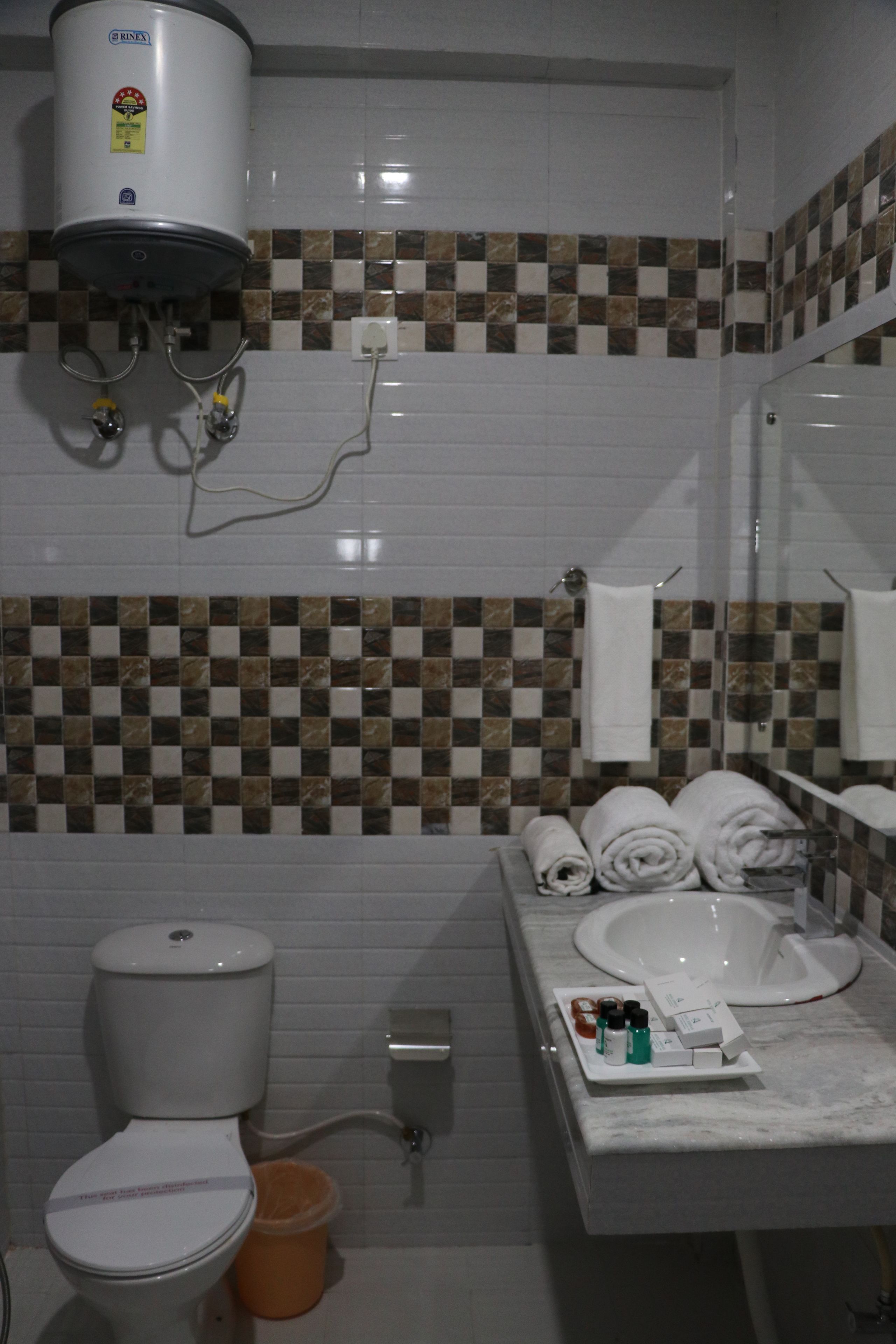 A bathroom with a toilet, a sink, a towel rack, and a hand dryer.