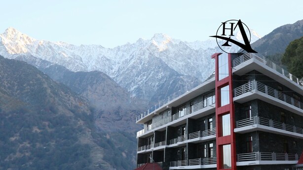 Ein mehrstöckiges Hotel mit Balkonen vor einer Kulisse schneebedeckter Berge.