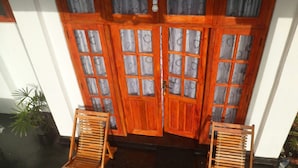 A wooden door with glass panels and a small step leading to a dark floor. There are two wooden chairs in front of the door. - Zircon Ella (Ella)