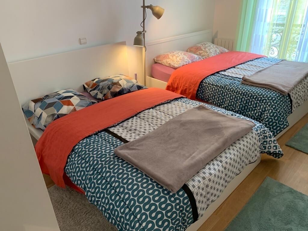A bedroom with two beds, each with patterned bedding and a red blanket.