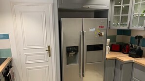 Ein Edelstahl-Kühlschrank mit digitaler Bedieneinheit, eine Mikrowelle und ein Mixer auf der Arbeitsplatte.