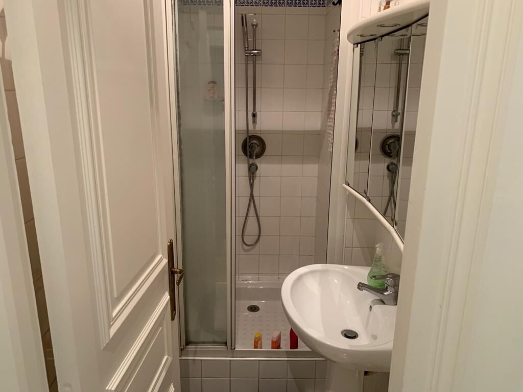 Une salle de bain avec une douche à parois de verre, un lavabo blanc et un miroir.