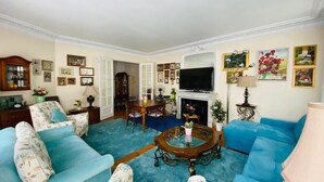 Ein Wohnzimmer mit blauen Sofas, einem Couchtisch, einem Kamin und einem Fernseher.