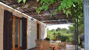 An outdoor patio with a covered seating area, a table with chairs, and a large flower arrangement. - Can Mostatxet, Country House in Can Picafort, Mallorca (Can Picafort)