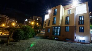 A multi-story building with balconies and a well-lit facade at night. - Hotel Ellegance (Tbilisi)