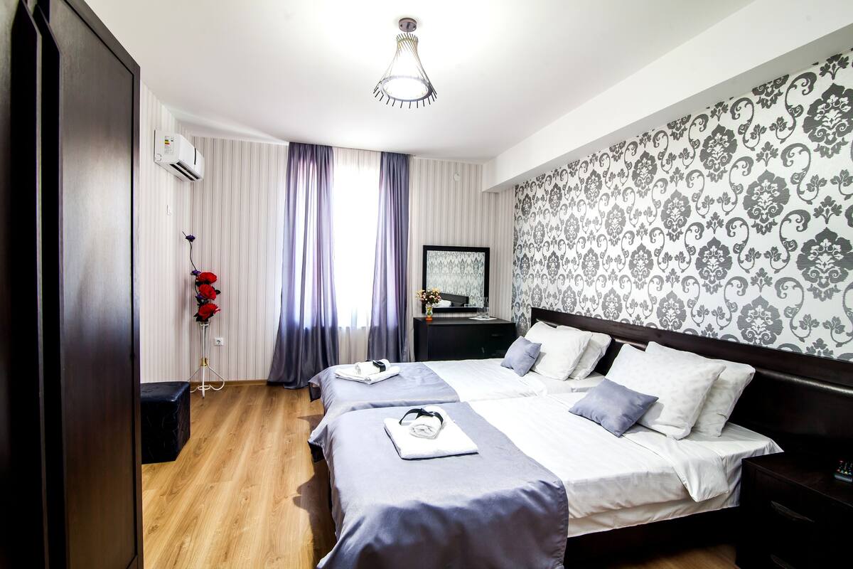 A hotel room with a large bed, a bedside table, a wardrobe, and a mirror.