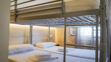 A bunk bed room with two beds, each with a pillow and a rolled towel.