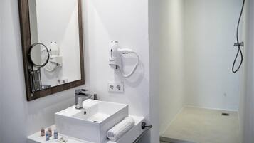Une salle de bain équipée d’un lavabo, d’un miroir, d’un sèche-cheveux et d’une douche.
