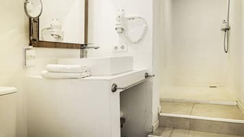 A modern bathroom with a toilet, sink, mirror, and shower.