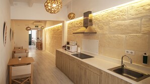 A modern kitchen with wooden cabinets, a stainless steel sink, and a stone wall backsplash.