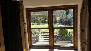 A window with a view of a garden and outdoor seating area. - Peaceful Rural Location Set Within 5 Acres Of Pasture and Woodland, pet friendly (Great Torrington)