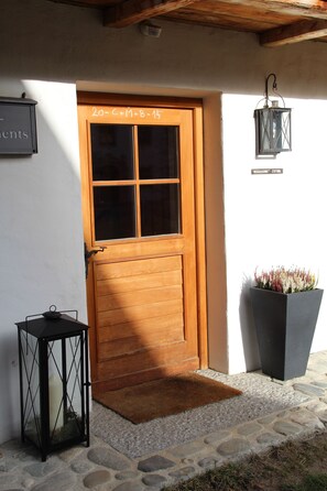 A wooden door with a glass panel, a black lantern, and a potted plant beside it. - Landhaus Schloss Anras (Anras)