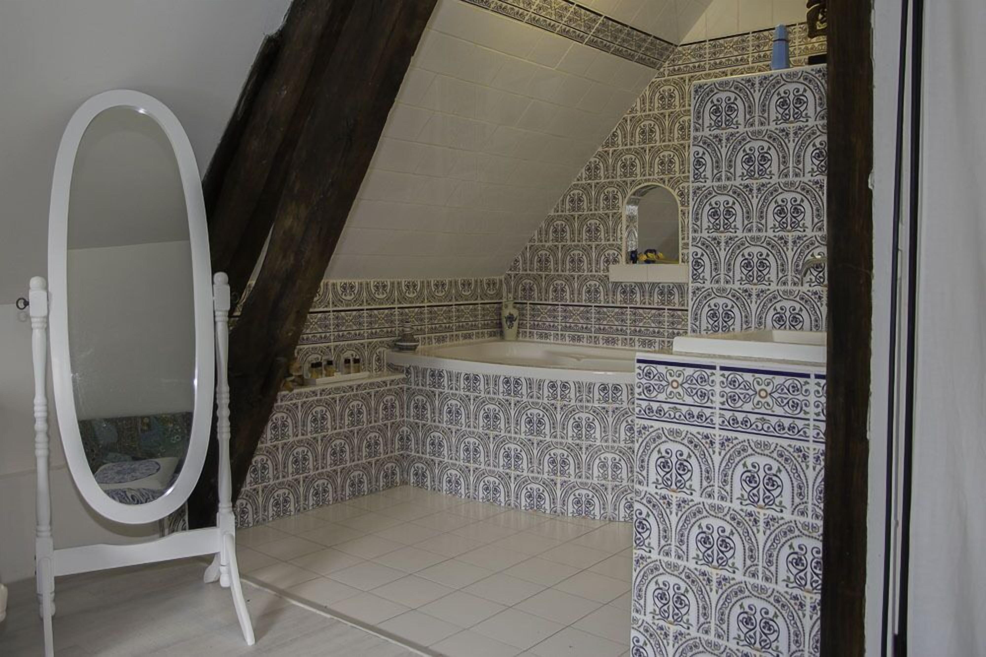 A bathroom with a white vanity, a freestanding mirror, and a bathtub.