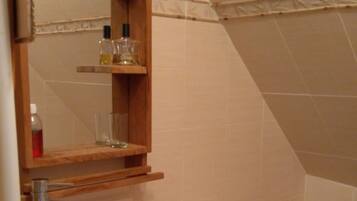 Een badkamer met een houten wastafelmeubel, een witte wasbak, een toilet en een spiegel boven het meubel.