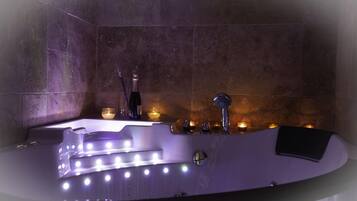 Un baño moderno con una bañera grande, zona de ducha y tocador con espejo.