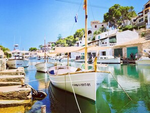 Un puerto deportivo con barcos amarrados, una escalera de piedra que baja hacia el agua y edificios con balcones y ventanas al fondo.