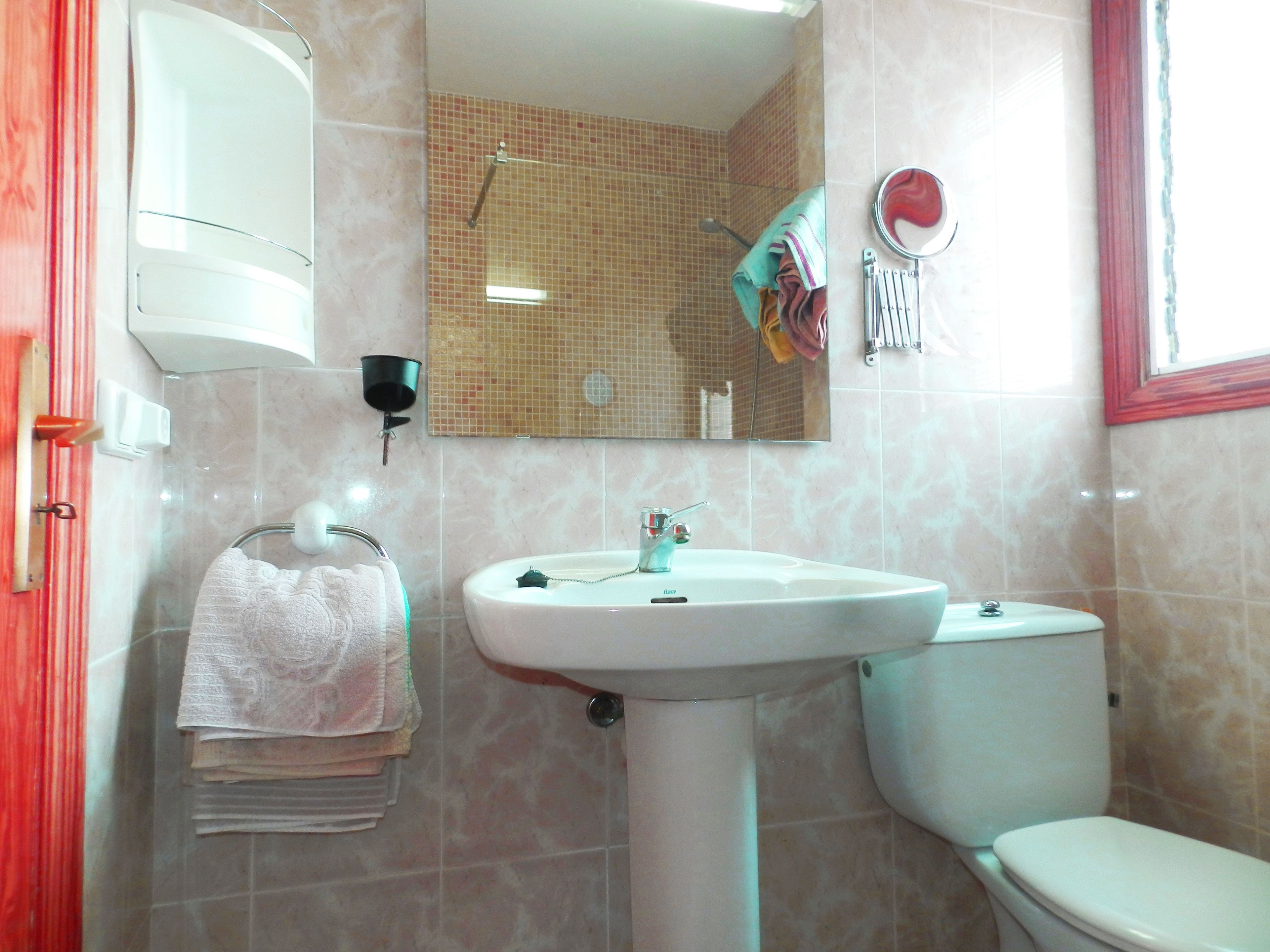 Un baño con lavamanos, inodoro y perchero para toallas.