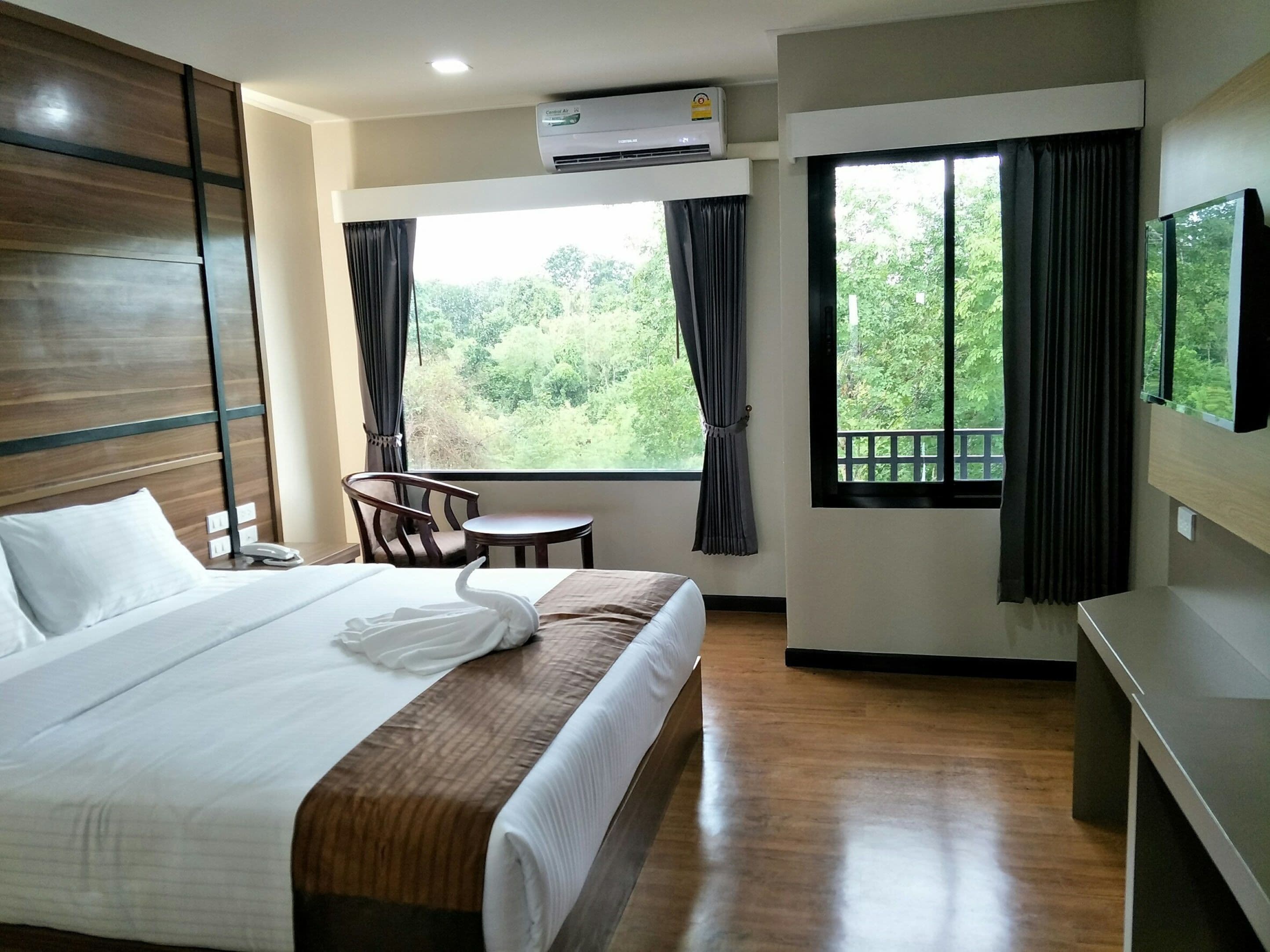 Une chambre d’hôtel avec un lit, une chaise, une petite table et un téléviseur fixé au mur.